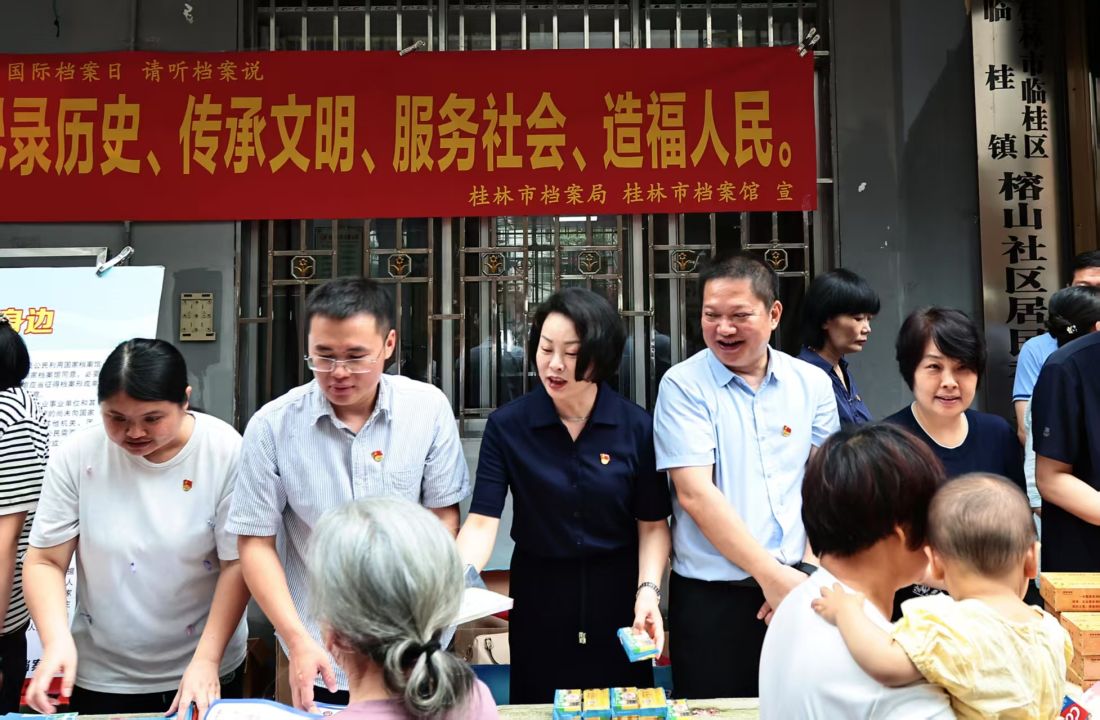 桂林市市委副秘书长、档案局局长钟涛（左四）和桂林市档案馆馆长李南海（左三）正在向群众赠送知识问答小礼品.jpg